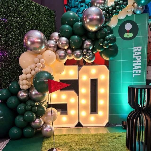 Arco de globos verde, plata y crema con números iluminados 50 para una fiesta temática de golf